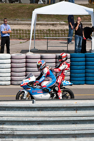 Simoncelli, winner of the 250cc Brno MotoGP on the back of Cluzel's bike. Simoncelli flubbed a winner's wheelie and destroyed his bike, so he need a ride back to the winner's circle.